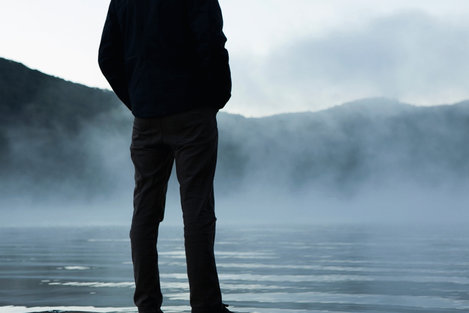 A man standing on a pier, looking out at the water